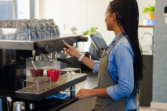 Commercial espresso machine preparing espresso shots into red mugs on countertop in coffee shop