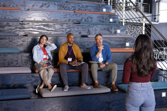 Asian Indian woman presenting to diverse panel in office meeting holding smartphone, copy space