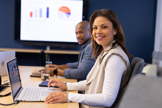 Diverse coworkers collaborating over charts in modern meeting room with silver laptop, copy space