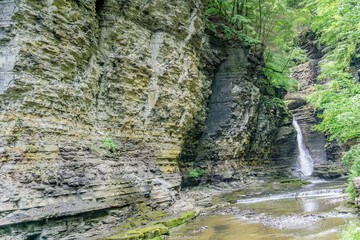 A rocky cliff with a waterfall and a stream