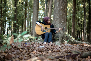 Woman playing guitar in forest