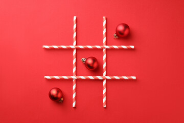 Tic tac toe game made with Christmas balls on red background, flat lay