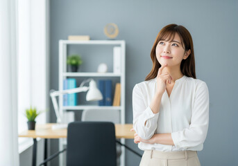 明るいオフィスで顎に手を添え未来のアイデアに思いを馳せる女性