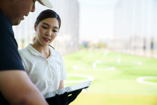 Golf instructor using launch monitor for swing analysis at modern driving range