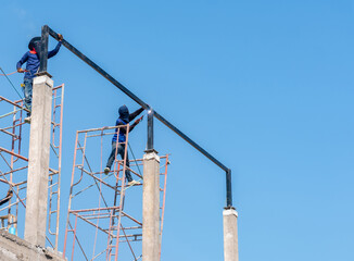 Worker welding a steel beam on concrete pillars.