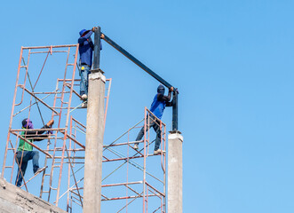 Construction workers on scaffolding aligning a large steel beam