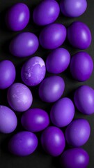 Overhead shot of dyed purple eggs, one with mottled pattern, on a dark, flat surface