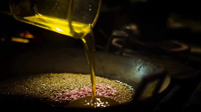 Warm golden oil being carefully poured over nuts and seeds in a big wok.