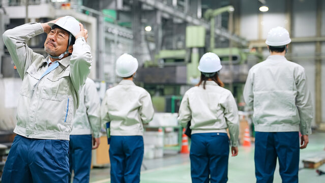 工場の中で部下に背を向けられショックを受ける作業員リーダー