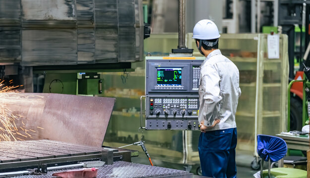 工場で操作盤で機械を操作する男性作業員