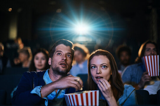 Couple watching movie with popcorn in cinema