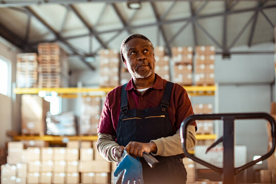 Senior warehouse worker holding gloves in distribution center