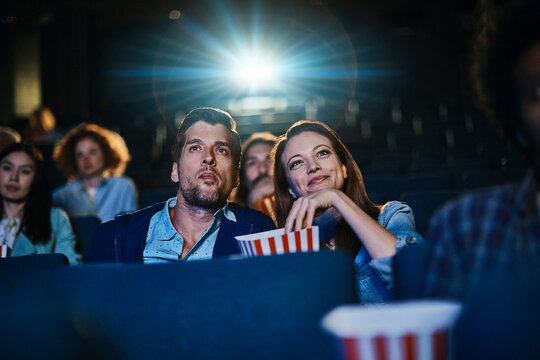 Young couple watching movie with popcorn in theater