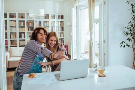 Two young women video calling in a bright home kitchen