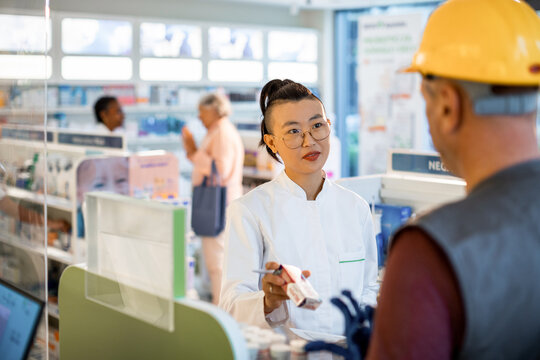 Pharmacist advising construction worker at pharmacy counter