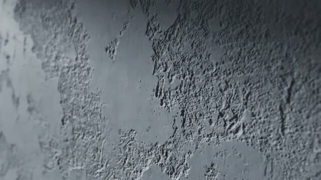 Close-up of a gray, textured surface with a rough, bumpy finish and a gradient lighting effect.