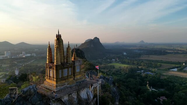 A statue of Jesus standing on a hill in Khao Khup Pha Sawan area, Pak Tho district, Ratchaburi province, Thailand, with houses and factories visible.