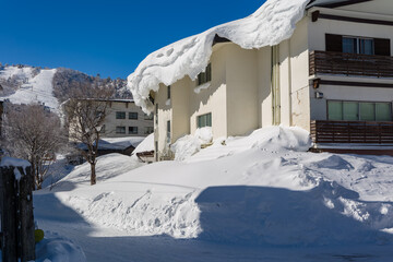 Deep snow banks and drifts covering a building exterior with blue sky background © whitcomberd