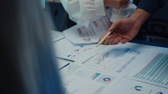 Close up Asia businesspeople meeting plan analysis statistics brainstorm and work with paperwork around table in office conference room at night. Business finance partners strategy investment success.