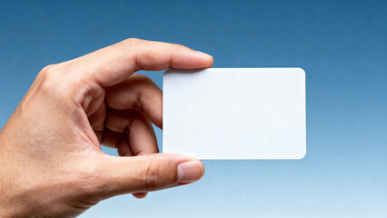 Fototapeta premium Close-Up Human Hand Holding Blank White Plastic Card With Clean Blue Background For Business And Branding Concept