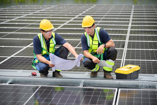 Engineers inspecting a solar panel installation, studying blueprints