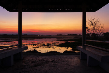 Nong Han Lake at Sunset with Pavilion Silhouette and Lotus Reflections in Red Orange Sky