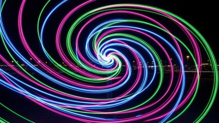 Mesmerizing light painting creates a vibrant, swirling spiral of blue, green, and magenta against a dark night sky, showcasing dynamic motion and ab...