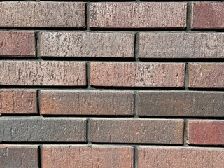 Obraz premium Close-up of a rustic, textured brick wall, showcasing weathered red-brown bricks and strong masonry. Perfect building background for design projects
