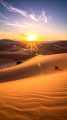 Sweeping golden sand dunes meet a bright, glowing sun at sunset, with scattered clouds