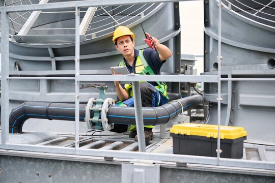 Engineer is inspecting a valve in front of the cooling tower