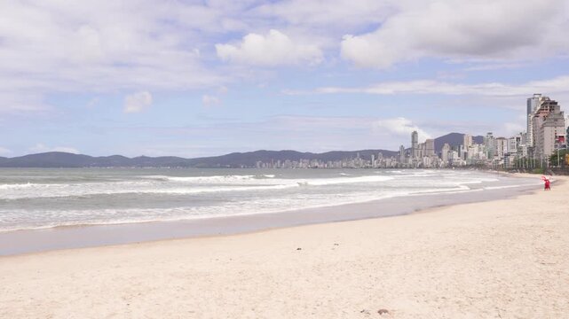 Itapema, Brazil: A beach with a city skyline and mountains in the background.
