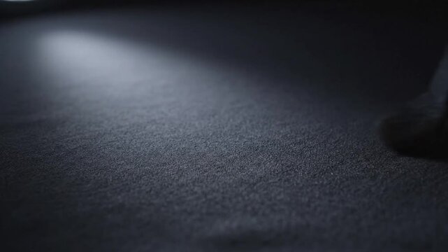 Close-up of a textured surface illuminated by a single spotlight with a dark background and a small