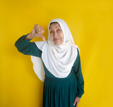 Old Lady In Hiab Showing Thumb Down Isolated Over Yellow Background
