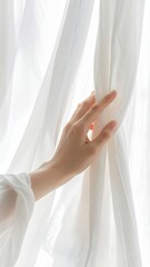 Gentle hand touches delicate white sheer curtains revealing bright daylight illuminating the room with soft ambient light creating a peaceful serene atmosphere