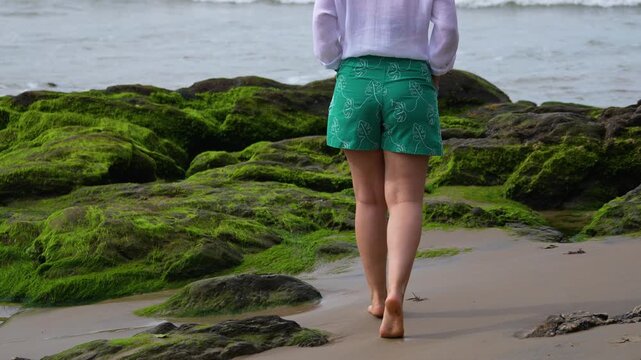 Woman walks on a mossy beach in Atalaia, Itajai, Brazil