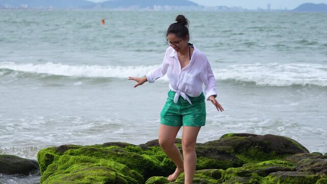Woman walks on a mossy beach in Atalaia, Itajai, Brazil