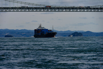 関門橋と関門海峡の波間に進むコンテナ船と満珠干珠20240224-3