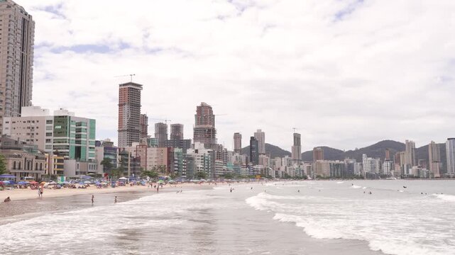 Itapema, Brazil: Beachgoers enjoy the ocean with a backdrop of city skyline.