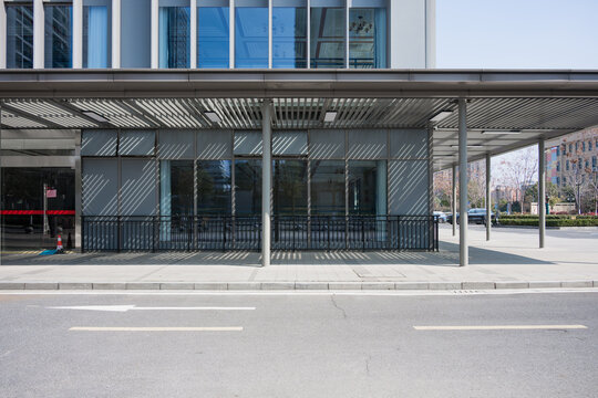 Modern building with glass facade and metal sunshade canopy on urban street