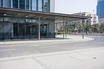 Naklejka premium Modern building with glass facade and street-side canopy shelter on an empty urban road