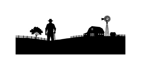 Silhouette of Cowboy Standing Near Farm Silo and Windmill