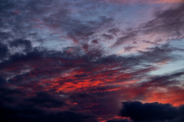 Obraz premium Vibrant red and purple clouds scattered across a dark twilight sky