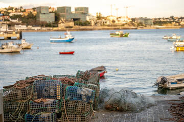 Fishing traps stacked beside harbor with anchored boats
