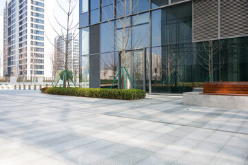 Fototapeta premium Modern glass facade office building with empty plaza and urban landscaping in daylight