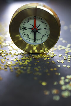Golden Compass on Dark Surface Surrounded by Glittering Sequins Reflecting Adventure and Direction