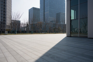 Fototapeta premium Modern urban plaza with empty paved ground and glass curtain wall buildings