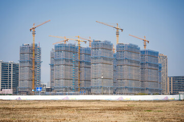 Multiple high-rise buildings under construction with numerous cranes and scaffolding on a large construction site