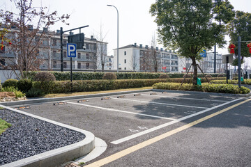 Empty urban residential parking lot surrounded by greenery and modern buildings on a clear day