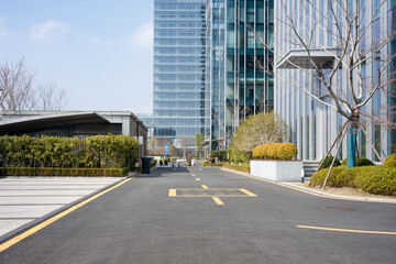 Obraz premium Modern glass curtain wall office building with empty road in front under clear sky
