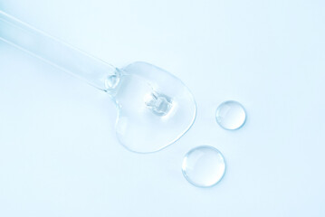 Drop of cosmetics and a pipette on a blue background. A product for skin, face or hair care.